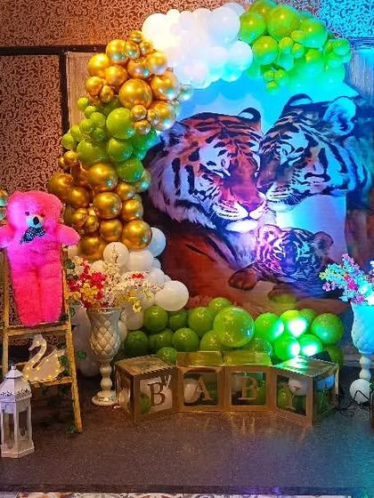 A wider view of the jungle and tiger-themed baby shower stage. The setup includes multiple teddy bears, 'BABY' blocks, and baby-themed cutouts to soften the wild theme.