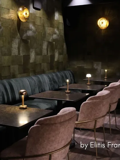 This moody and opulent commercial space features a dark, textured wallcovering by Élitis France. The design creates an atmosphere of sophisticated charm, proving that the right wallpaper can define the character of a bar or restaurant.