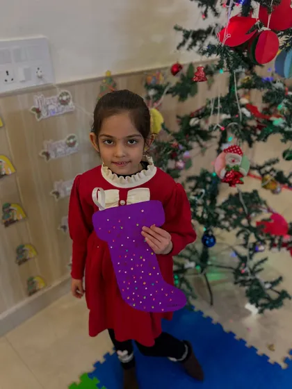 A girl holds up her beautifully decorated purple stocking.