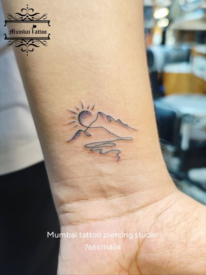 A beautiful minimalist tattoo depicting a sun rising over mountains and a river, all in one continuous line. This design is a testament to our creativity in crafting meaningful landscapes with the simplest of forms.