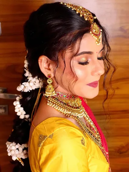 A close-up of the bride's makeup, featuring golden eyeshadow and a bold magenta lip, perfect for a vibrant Haldi or wedding ceremony.
