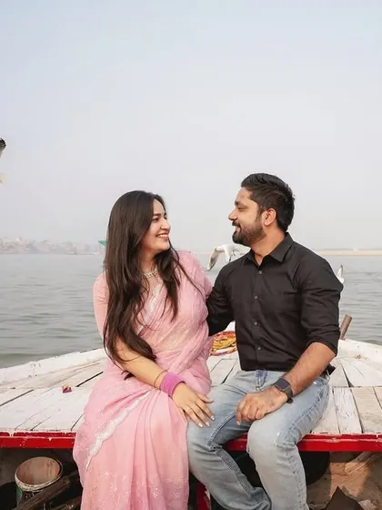 Another beautiful angle from the boat photoshoot in Banaras. This image captures the couple's happy interaction with the scenic river and birds in the background.