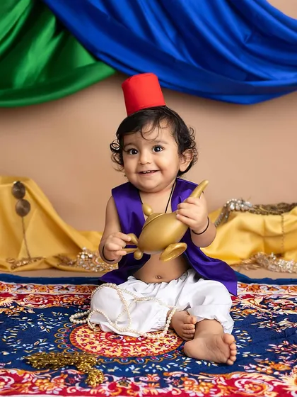 Holding his magic lamp, this little boy's smile is pure magic. The colorful draping in the background adds to the Arabian nights feel.