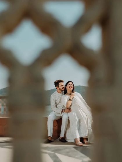 A candid, happy moment shared between the couple, framed by the intricate patterns of a palace lattice screen.