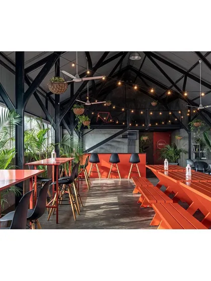 Bright orange picnic tables and high-top counters add a pop of vibrant color to the industrial rooftop space. This choice makes the environment feel energetic and fun, suitable for social gatherings and team-building events.