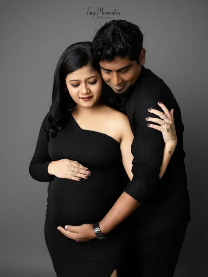 The gentle placement of hands and the soft expressions make this a deeply emotional portrait of a couple cherishing the life they've created.