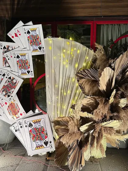 Our popular Diwali taash party photo prop. This installation features oversized playing cards, a backdrop of soft drapes and fairy lights, and a modern arrangement of dried pampas grass.