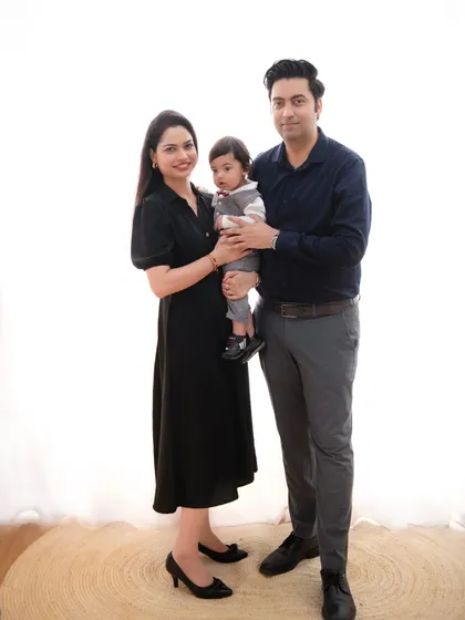 A formal family portrait against a bright, clean backdrop. The family's dark, formal wear creates a sophisticated and elegant look, perfect for a timeless keepsake.