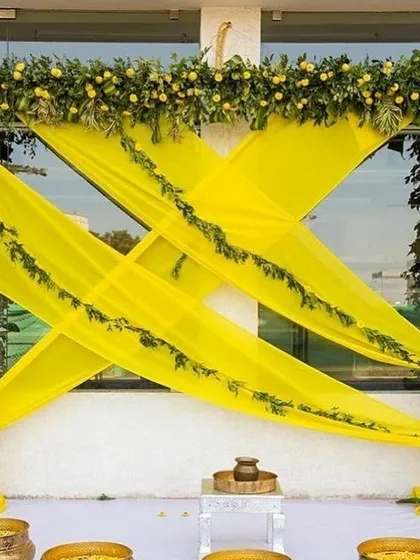 A fresh and traditional Haldi decor. The bright yellow drapes are perfectly complemented by a frame of real greenery and lemons for a zesty touch.