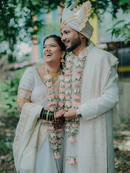 The pure joy of a newly married couple. Varsha and Prasad share a laugh, their varmala garlands adding a touch of floral beauty to their traditional attire.