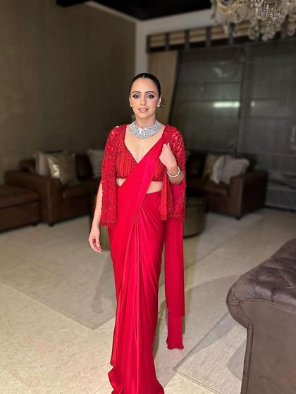 The full-length view of this stunning red saree look. The makeup is bold yet sophisticated, perfect for a cocktail or reception event.