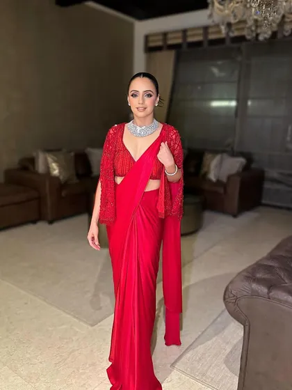 The full-length view of this stunning red saree look. The makeup is bold yet sophisticated, perfect for a cocktail or reception event.