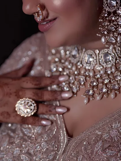 A detailed shot of a bride's hand on her chest, showcasing her intricate jewelry, mehendi, and nails.
