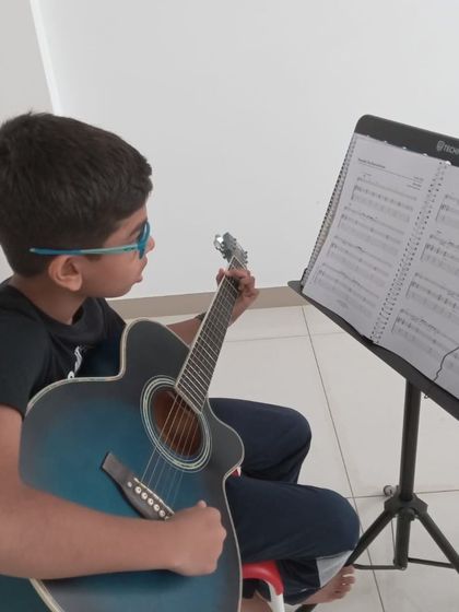 A student reading sheet music while practicing the guitar.