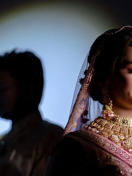 An artistic portrait using a shadow silhouette of the groom against the bride. This creative lighting technique tells a story of connection and presence.