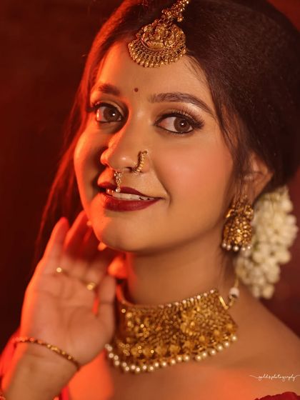 Portraits from a makeup shoot, showcasing a model in a classic red and cream saree. The images highlight the flawless makeup and traditional styling in a beautiful garden setting.