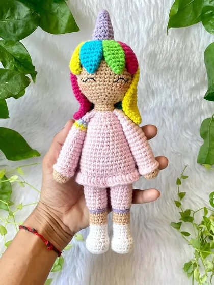 A magical unicorn doll with rainbow hair and a sparkly horn. She is dressed in a cozy pink outfit and is ready for enchanting adventures.