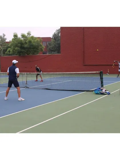 Players engaged in a doubles match, showcasing the ample space and clear markings of our hard courts. We ensure the entire playing area is maintained to professional standards.