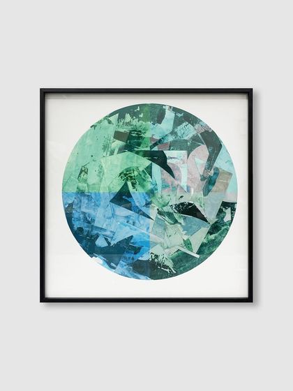 A circular abstract collage of green and blue tones is neatly presented in a square black metal frame, creating a compelling visual contrast between shapes.