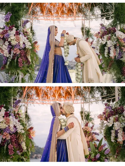 A close-up of the varmala exchange, where the groom bows his head in a gesture of love and respect. This moment, framed by the soft pastel florals of the mandap, captures the beautiful blend of tradition and emotion.