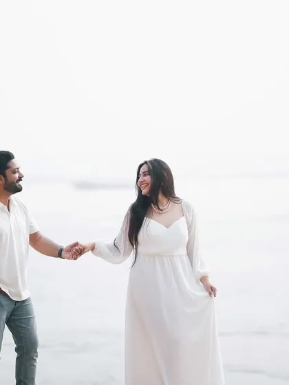 A bright and airy shot of the couple walking along the riverbank. The simple white outfits and natural setting create a feeling of effortless romance.