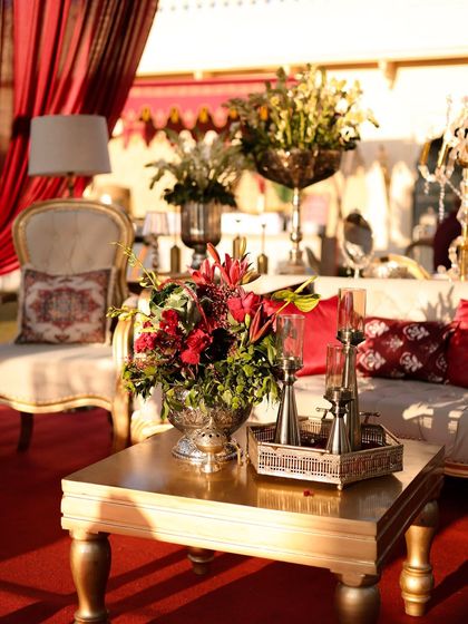 A close-up of a coffee table, where a silver floral vase and a tray of candles sit atop a gold-finished table. It's this mix of metals and rich colors that creates a layered and sophisticated look.