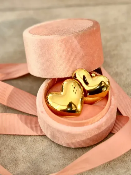 A close-up of our chunky gold-tone heart earrings, nestled in a plush pink velvet box. This is the perfect modern and romantic gift to show your love this Valentine's Day.
