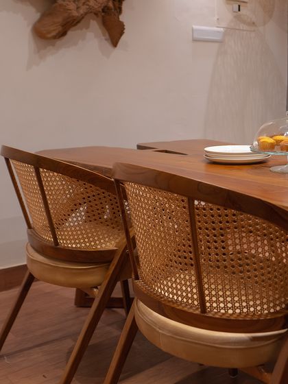 Another angle of the 'Modis' dining chairs, showing how the curved back wraps around for comfort. The cushioned seat adds to the inviting feel.