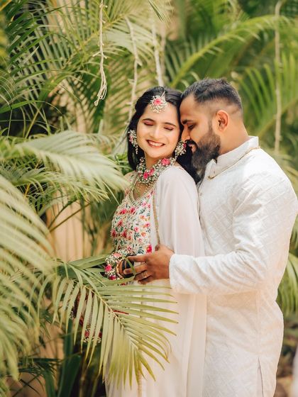 A serene moment between the couple during their pre-wedding ceremonies, dressed in traditional attire. The lush green background adds a natural touch.