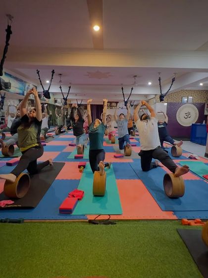 A beautiful shot of the class in a low lunge with a backbend, supported by the yoga wheel. This pose opens the hips and chest wonderfully.