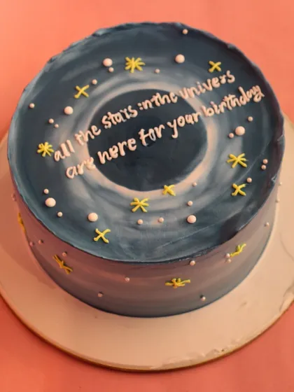 A top-down view of the galaxy cake, showing the swirling universe design and the message "All the stars in the universe are here for your birthday."