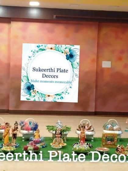 A 21-plate seer varisai arrangement on a grass floor for a baby shower in Madukkarai. The setup includes traditional lamps (kuthu vilakku) for an auspicious touch.