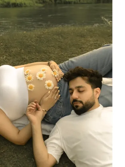 A sweet and playful detail. Daisies are arranged on the mother-to-be's belly as she and her partner relax on the grass, a creative and charming way to celebrate new life.