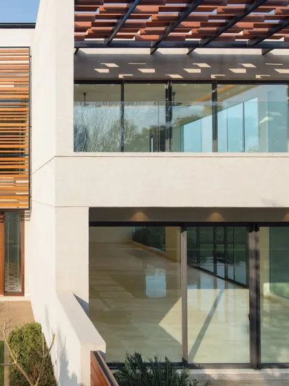 Wooden screens and pergolas add warmth and texture, contrasting with the cool white walls. This interplay of solid and void blurs the boundaries between indoors and outdoors, while maximizing natural light and ventilation.