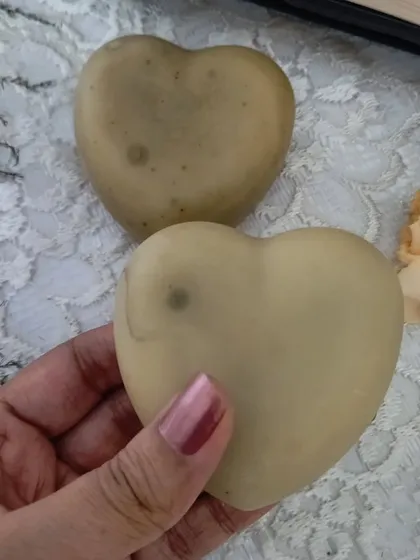 Holding a 'Hope' heart soap. It's made with creamy coconut milk for a rich, moisturizing lather.