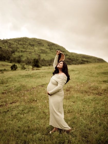 A graceful and elegant pose. The mom-to-be stands in a field, holding her hat up to the sky, her dress flowing around her. It’s a portrait of strength and beauty.