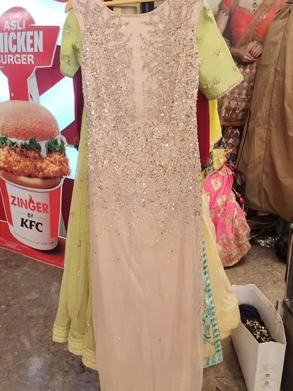 A full-length view of a heavily sequined gown in a soft beige hue with contrasting lime green sleeves. This unique sample piece showcases the kind of designer finds available during our clearance sales.