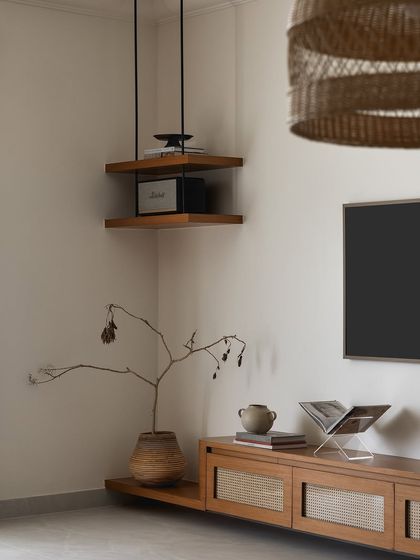 A minimalist TV unit with a floating wood and cane console. The corner ledge and suspended shelf provide extra surfaces for decor and electronics.