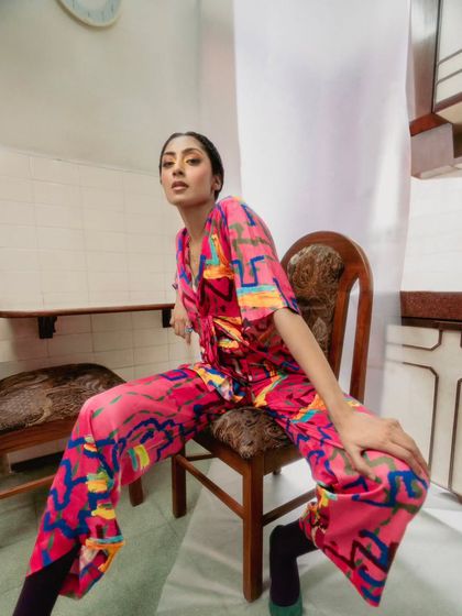 Another look from our creative shoot for Advait, featuring a colorful pink printed jumpsuit. The model's relaxed yet strong pose on the vintage chair creates a compelling mood that is both artistic and effortlessly cool.