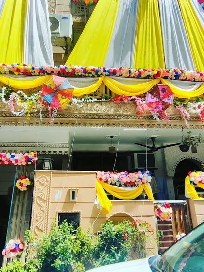 A beautiful home decorated with yellow and white drapes, accented with colourful kites and floral arrangements for a unique theme.