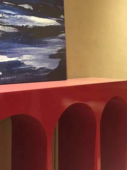 A behind-the-scenes shot of the red console before the final styling. Even on its own, the piece has a strong presence due to its unique arched design and vibrant color.