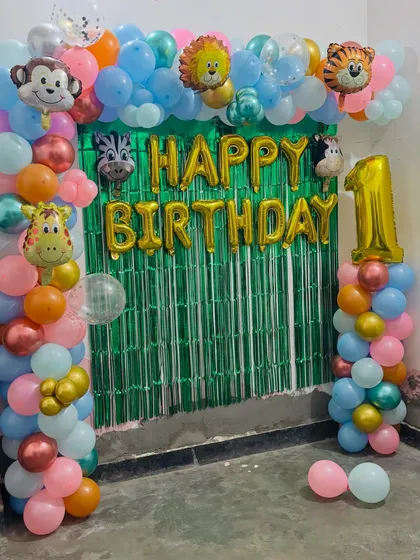A colorful jungle-themed first birthday arch. I used a green tinsel backdrop and lots of friendly animal foil balloons like a monkey, lion, and giraffe.