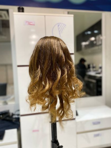 The final result of a styling practice session on a mannequin, featuring perfectly formed, glossy curls.