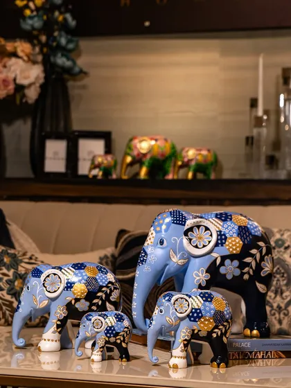 A family of elephants featuring a beautiful blue and gold patchwork design. Placed in a living room setting, they show how art can bring personality and a meaningful narrative to your home decor.