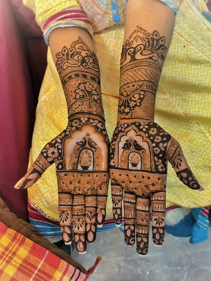 This beautiful mehndi was for the groom's sister. It features detailed figurative work, including birds in a 'jharokha' or window, combined with peacock motifs on the arms.