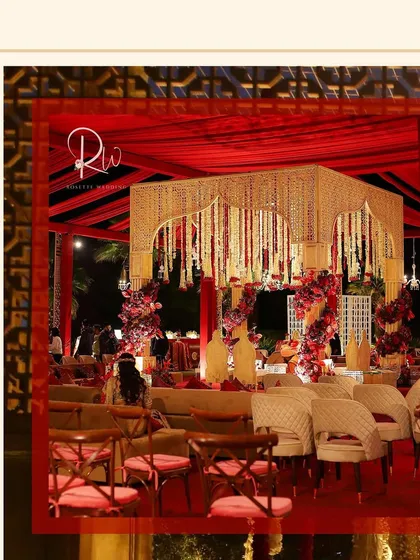 A wider view of the wedding setup, showing the mandap and guest seating. The entire space is unified by the red and gold color palette.