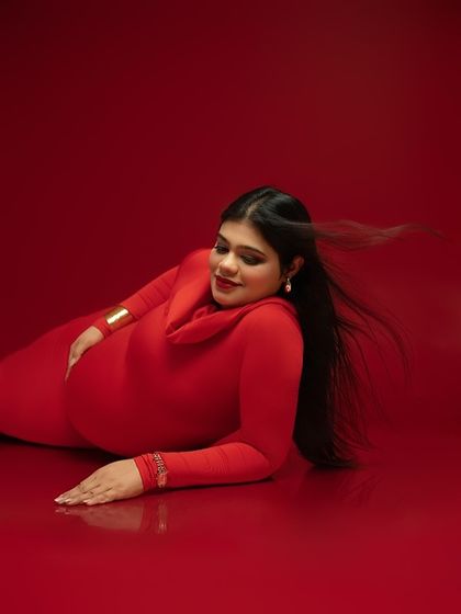 Grace in every line. This reclining pose is both elegant and strong, showcasing the beautiful curve of the baby bump against a bold red backdrop. The subtle motion in the hair adds a touch of life and softness.