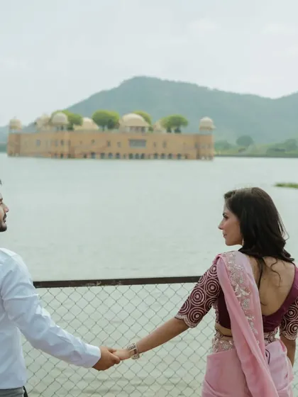 A "follow me" style shot with the beautiful Jal Mahal in the background. This pose creates a sense of journey and togetherness, perfect for a pre-wedding story.