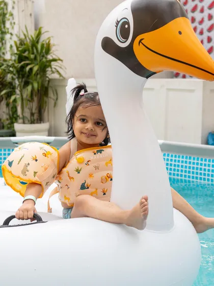 This little girl looks so content sitting on her inflatable swan, complete with arm floaties for extra safety. It is a perfect, relaxed moment during a fun-filled day.