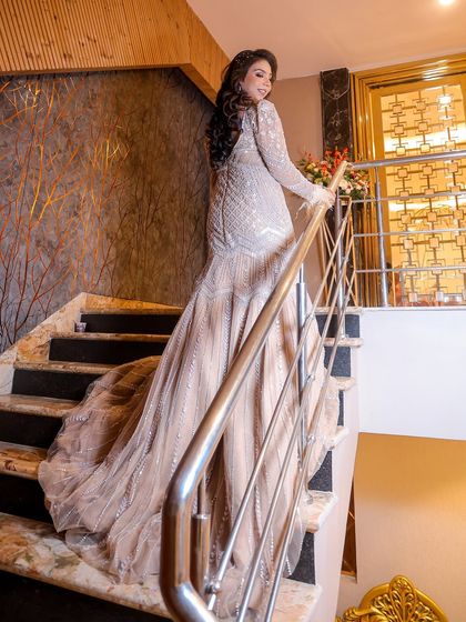 An elegant full-length shot of the bride, Yashika, showcasing her stunning gown. The pose on the staircase adds a touch of glamour and sophistication to her bridal portrait.